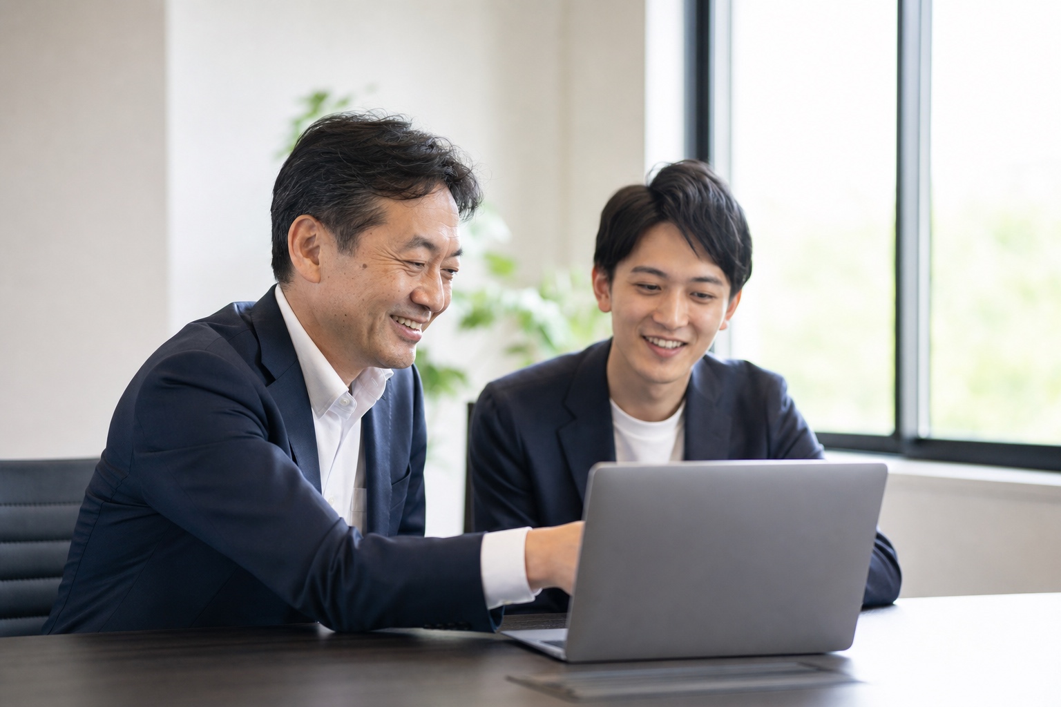 パソコンを見ながら打ち合わせをする経営者と担当者